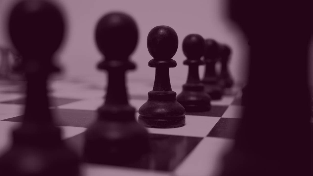 Row of black chess pawns positioned on a checkerboard.