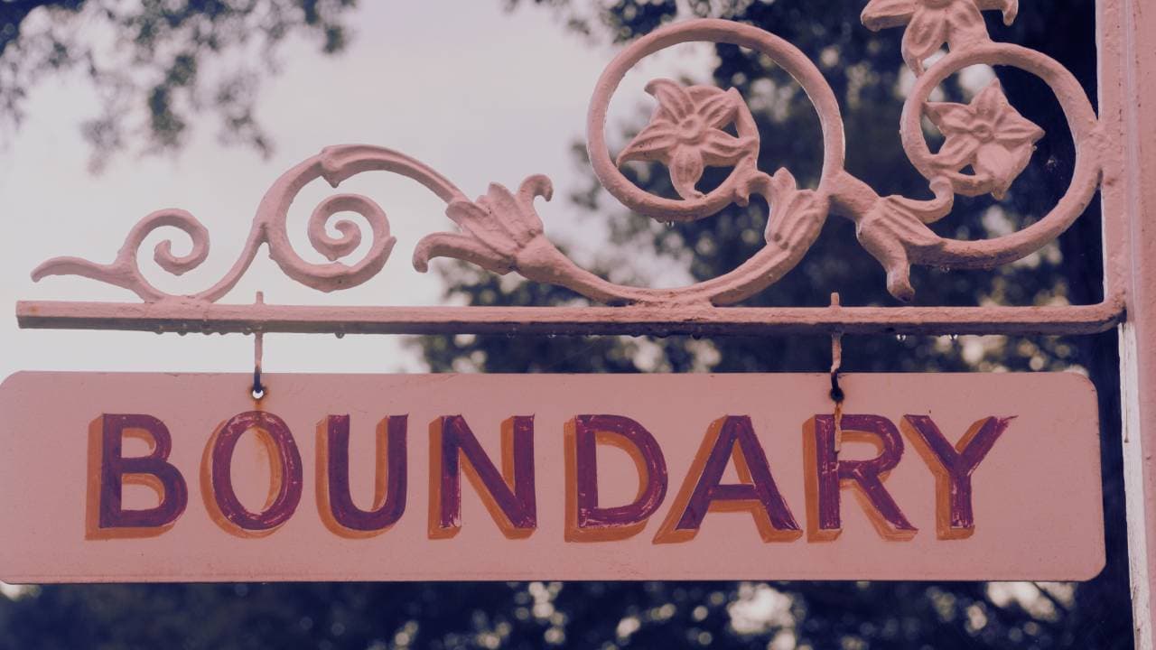 Pink sign with the word “BOUNDARY” displayed prominently, decorated with floral elements.